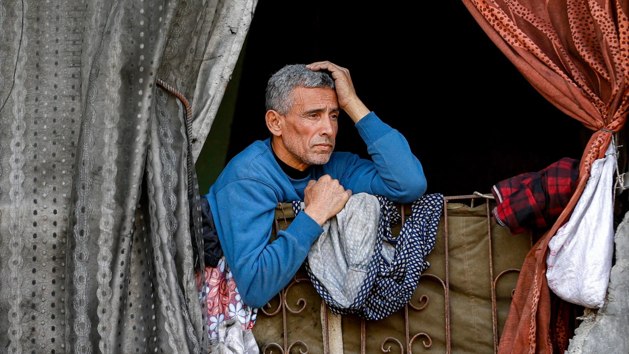 A man watches from a destroyed house in Gaza City on 7 February 2026 (AFP/Omar al-Qattaa)