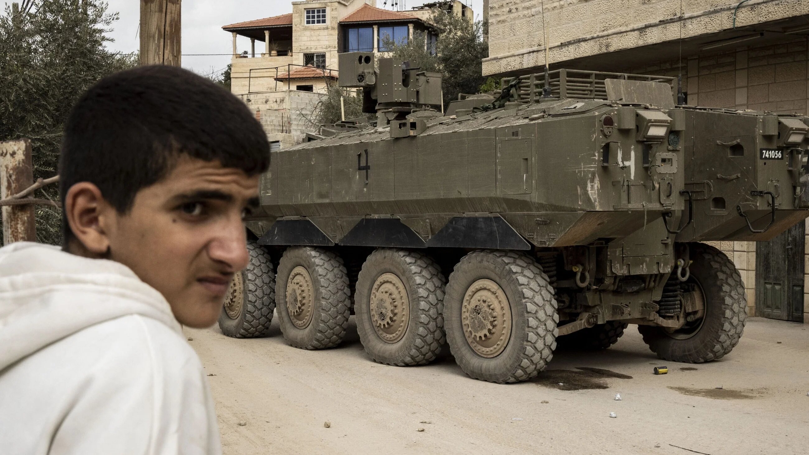 A Palestinian boy stands nearby a military vehicle during an Israeli raid in Jenin, occupied West Bank, 17 February, 2026 (AFP/John Wessels)