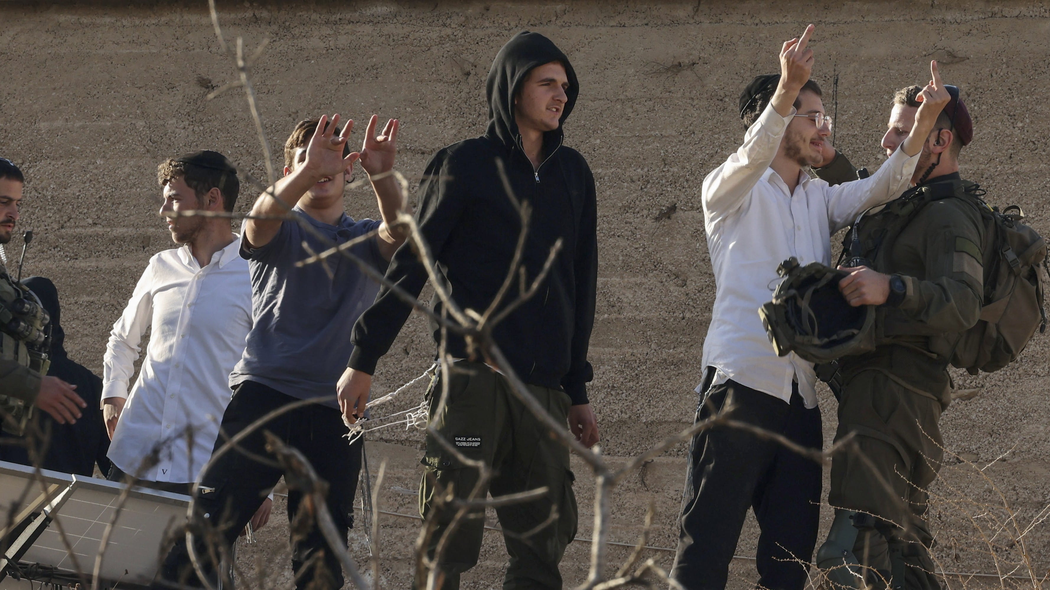 Israeli settlers flash middle fingers taunting Palestinian locals nearby the Ibrahimi Mosque (AFP))