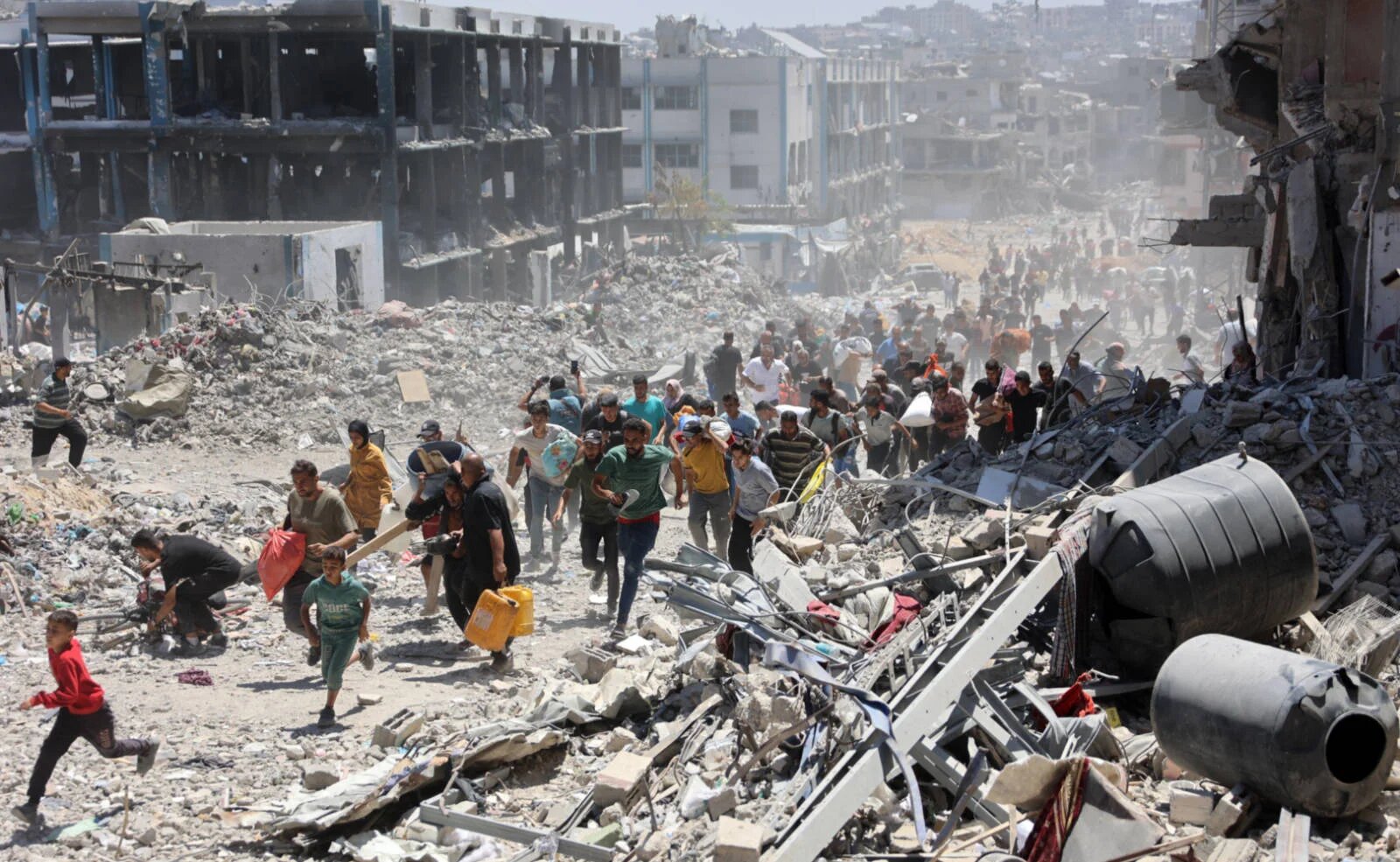 Palestinians who returned briefly to the Jabalia refugee camp in the northern Gaza Strip run for cover after a school was hit by an Israeli strike on 30 May 2024 (AFP)