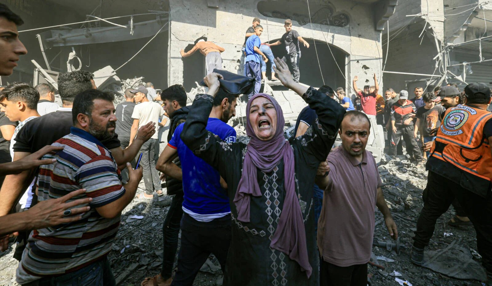 A Palestinian woman reacts as others rush to look for victims following an Israeli strike in Khan Yunis in the southern Gaza Strip on 17 October 2023 (AFP)