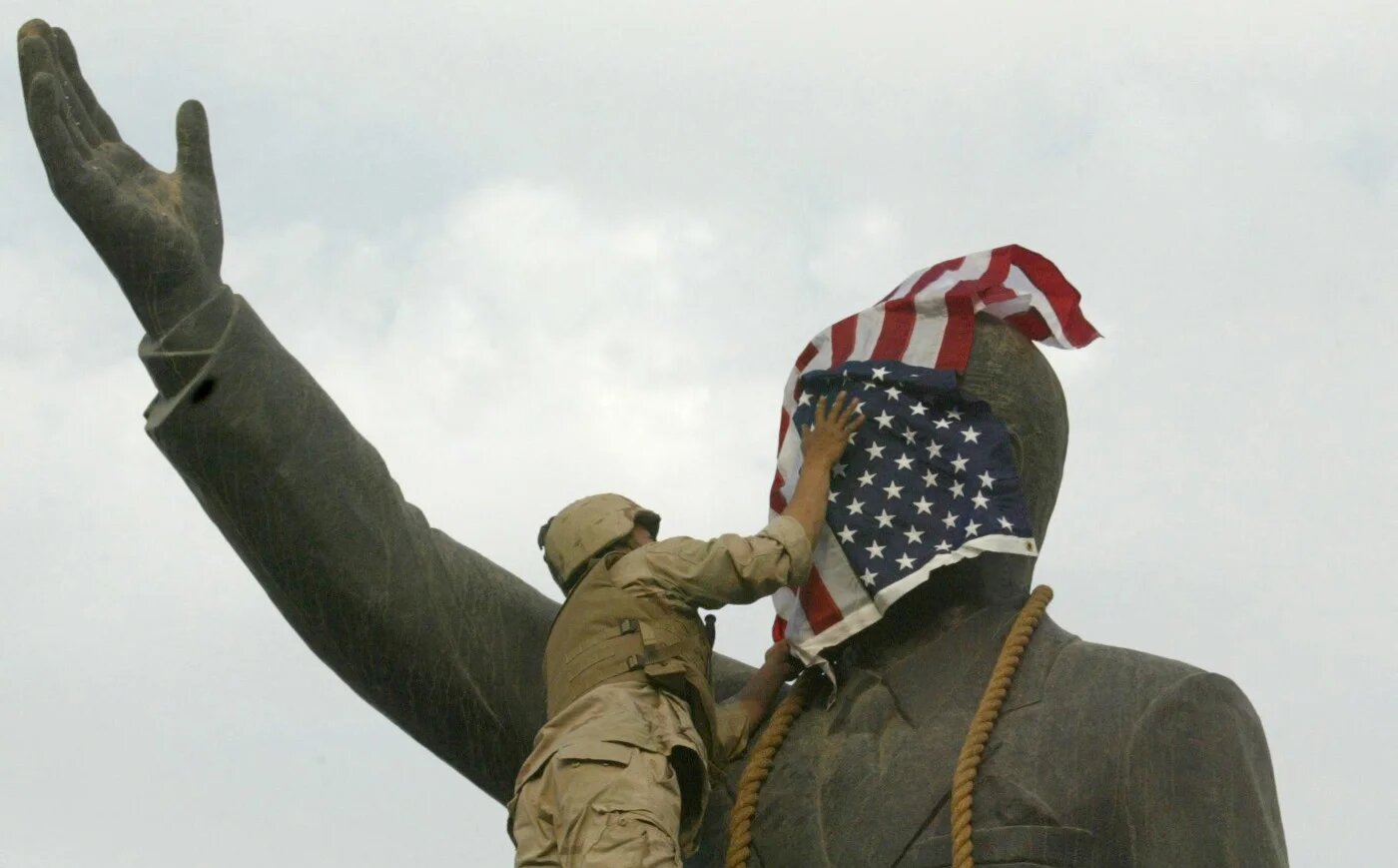A US Marine covers the face of Iraqi President Saddam Hussein's statue with the US flag in Baghdad's al-Firdos Square on 9 April 2003 (AFP)