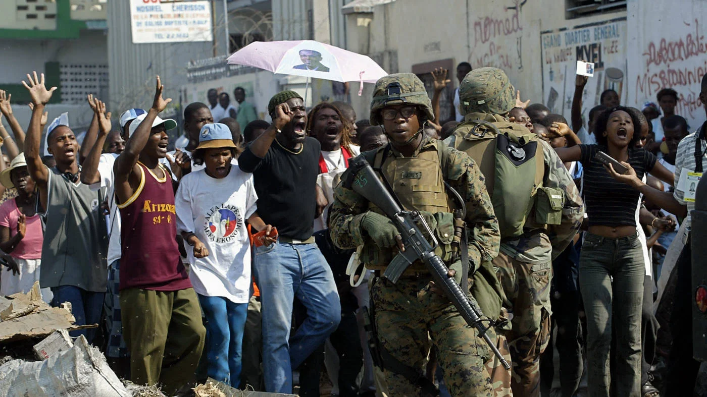Supporters of former Haitian president Jean Bertrand Aristide shout at a squad of US marines in Port-Au-Prince on 8 March 2004 (AFP) 