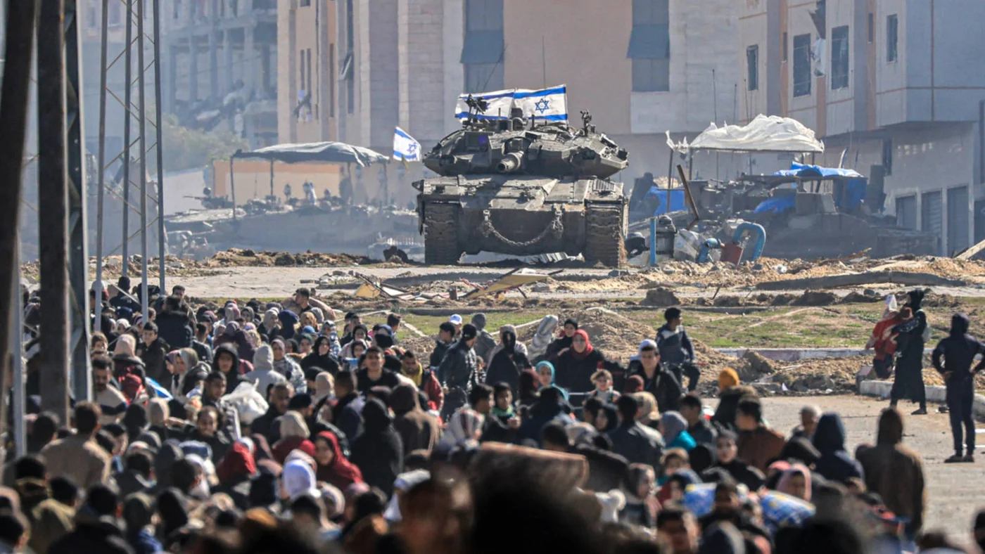 An Israeli tank overlooks Palestinians fleeing Khan Yunis in the southern Gaza Strip on 26 January 2024 (AFP)
