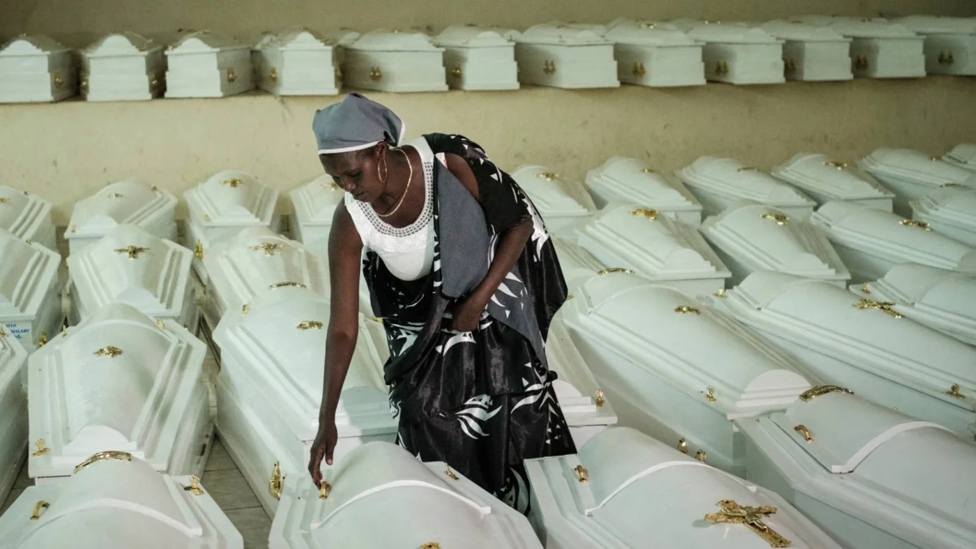 A survivor of Rwanda’s 1994 genocide with coffins which contain remains of victims at the Nyanza Genocide Memorial in Kigali in May 2019 (AFP)